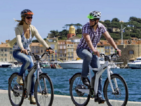A couple riding ebikes near water, showing the best ebike brands.