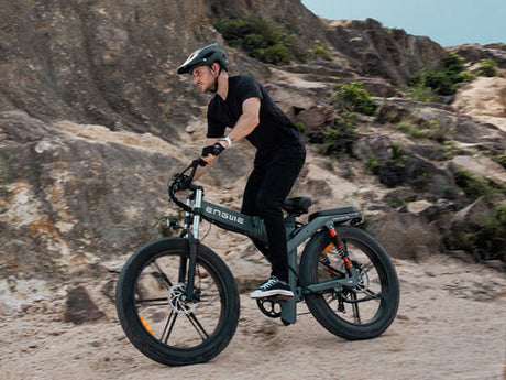 a man riding a black engwe x26 fat tire electric bike on the sand