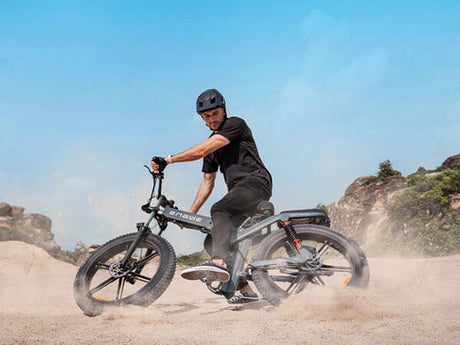 a man riding a black engwe x26 on the sand