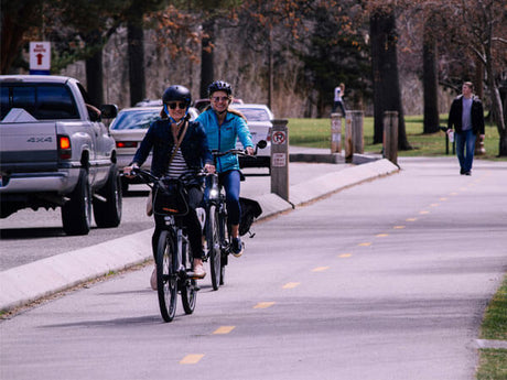 two people riding electric bikes on the street